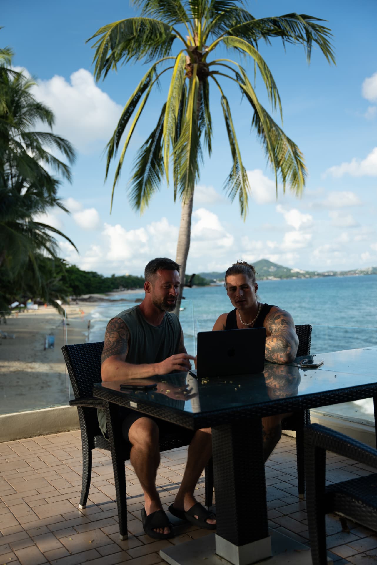 Timon and Marius reviewing work on a laptop by the beach